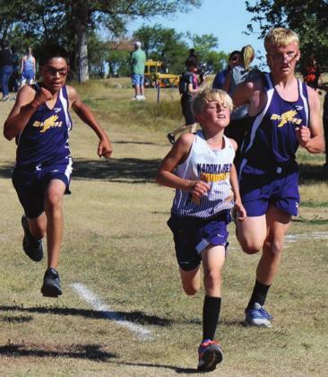 ABOVE LEFT: Dupree’s Tripp Schrempp (L) and Case DePoy converge on either side of a Kadoka runner as they approach the finish line in cross country action at the LMC meet Saturday. Photo by Patty Peacock