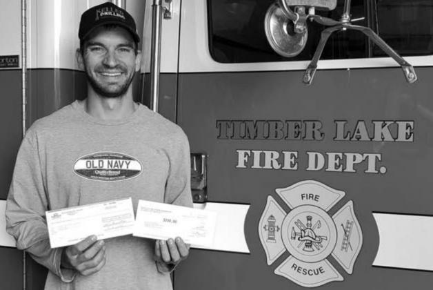 Scott Biegler of the Timber Lake Volunteer Fire Dept. accepts a $500 donation from Moreau-Grand Electric and Basin Electric.