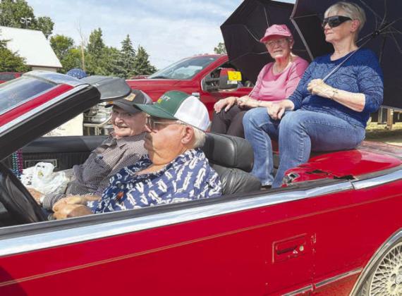 Parade marshals, driven by Marty Biegler in his red convertible, were (front) Rod Enright, his wife Mavis Enright (in blue) and her sister, Frances Marshall (in pink).
