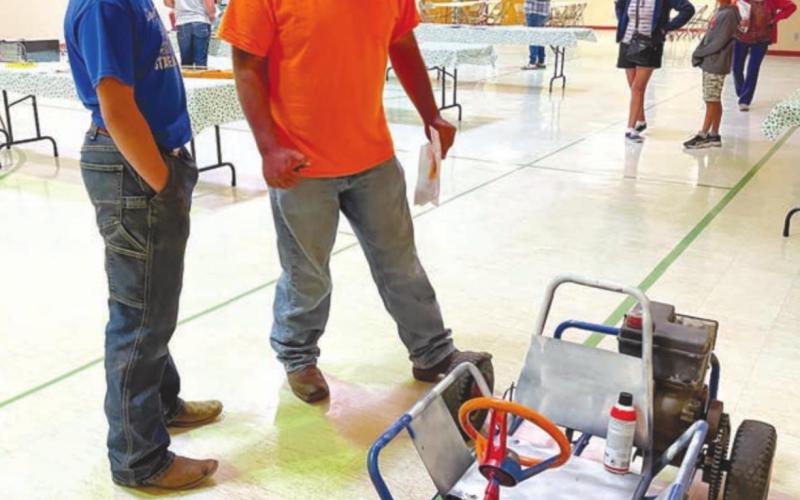 Jerimiah Garon, the judge, talks with 4-Her Levi Berndt about the motorized go cart he built using a lawn mower motor.