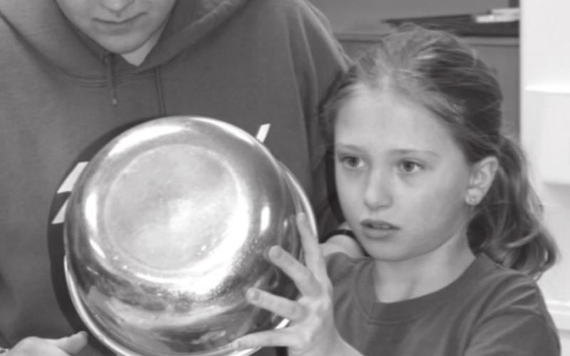 Erin Lemke, an older 4-H member, works with London Wishard as they mix and pour the filling for a breakfast quiche.