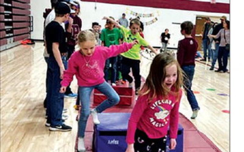 TOP RIGHT: High school volunteer Gabe Keller helps Maya Peterson with a robotics activity. MIDDLE RIGHT: Roger Lawien of Moreau-Grand Electric shows Jett Fiddler the protective gear that linemen wear. BOTTOM RIGHT: Kids put their balance, strength and coordination skills to the test.