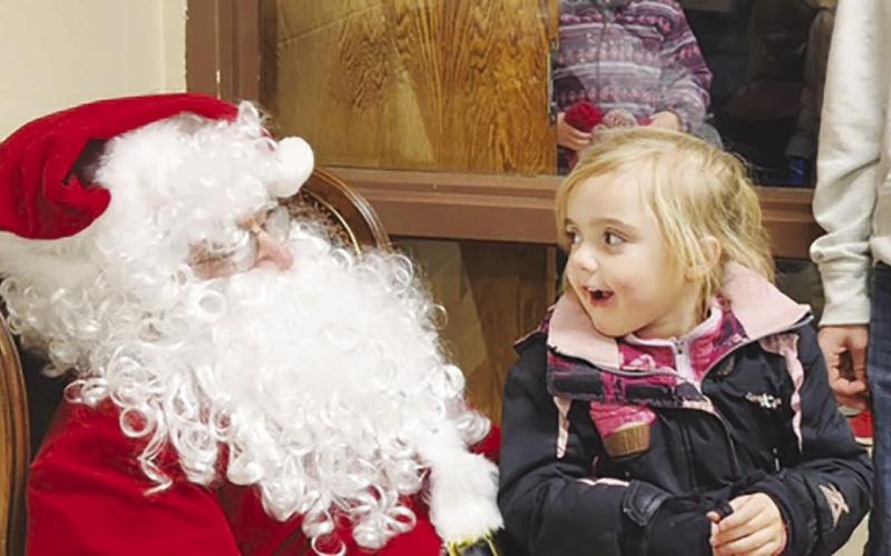Five-year-old Lydia O’Bryan reacts with wide-eyed amazement at meeting Santa Claus during Timber Lake’s Holiday Extravaganza on Friday, Dec. 1. Lydia, daughter of Vicky Hulm and Taylor O’Bryan, said she’s been a good girl and asked Santa to bring her a stuffed cheetah. Photo by Roger Lawien