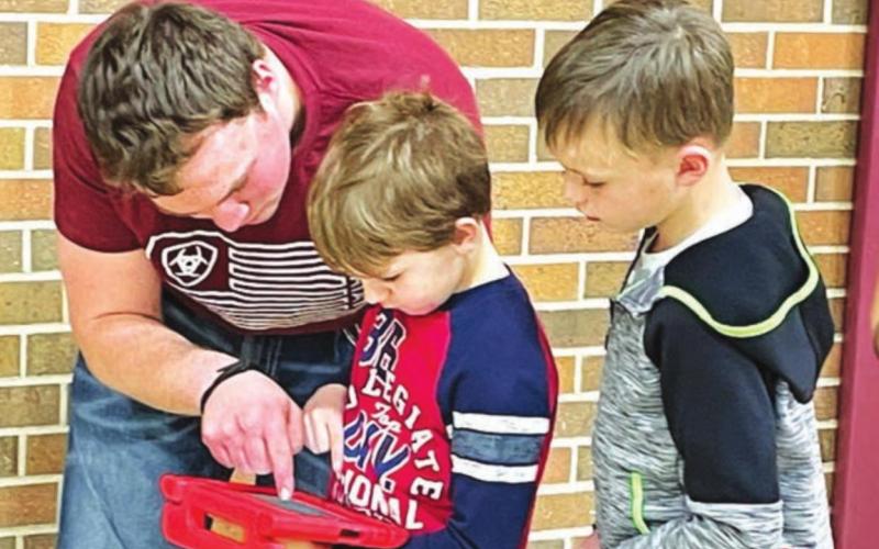 High school student A.J. Lindskov instructs Barrett Maciejewski and Keaton Jones on how the robotics remote works.