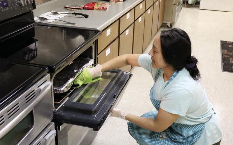 Gina Simon, manager of the Timber Lake-Isabel Senior Meals Site located in the Timber Lake Community Center, checks on a dish in the oven while preparing boxes for delivery through the Meals on Wheels Program. The program serves 25-30 clients per day, five-days-a-week. The program is slated to discontinue service this Friday, Sept. 13. Photo by Jon Flatland