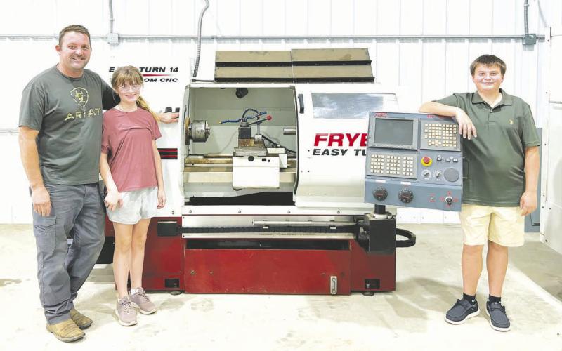 Heinrich Muller (left) with his children, Cecilia (middle) and Conrad (right) with some of the machinery in the new KOTA shop.