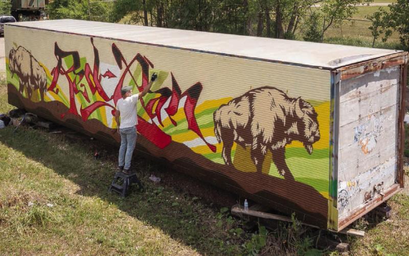 An artist works on a mural in Eagle Butte during the 2022 RedCan Graffiti Jam. The 9th annual event got underway Wednesday and continues through Saturday. (Photo by CRYP)