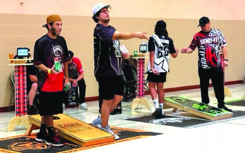 CJ Johnson, Scotty Landreaux, Bryson Andrews and Brad LeCompte compete in cornhole during a recent league night in Timber Lake. Below, James Traversie and Cadillac Ward display the Cheyenne River Cornhole League banner. Photos by Kathy Nelson