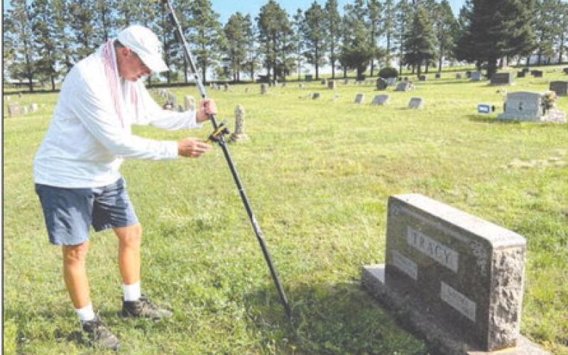Benton Smith of Sentry Mapping Services in Oxford, MS, logs in GPS coordinates and photographs a headstone as part of a mapping project at the Timber Lake Cemetery. Photo by Jon Flatland