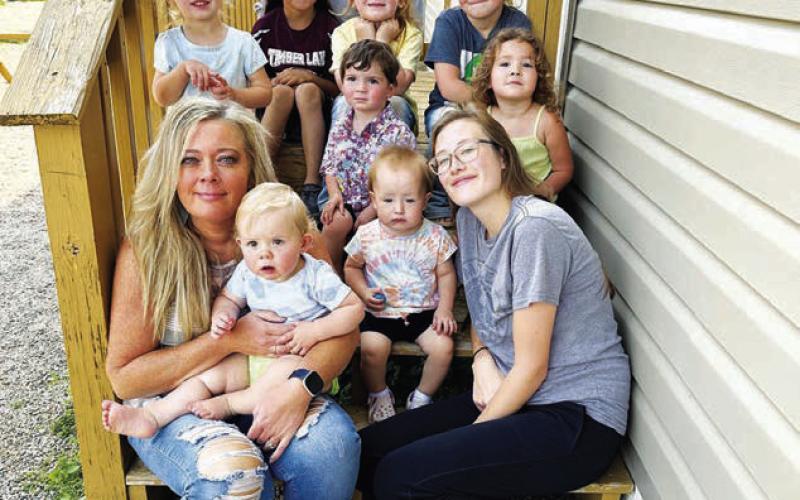 Stacy Keller (front, left) is the new interim director of Timber Lake Community Daycare. She is pictured holding Carsyn Leibel. Colty Claymore is at right with Kasen Pay Pay. In the middle row are (l-r) Marin Maher, John Booth, and Jensen Booth. In back are Kian Rousseau, Christina Rousseau, Autym Jones, and Wren Jones.