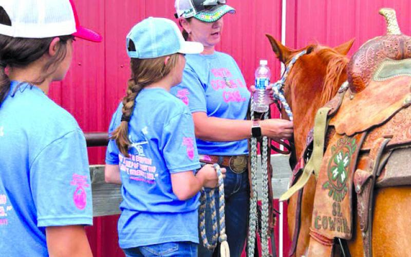 Shanna Gebhardt, right, shows two Cowgirl Heaven Camp participants some of the finer points to tying a knot during the camp’s 20th anniversary in June. Photo by Jon Flatland