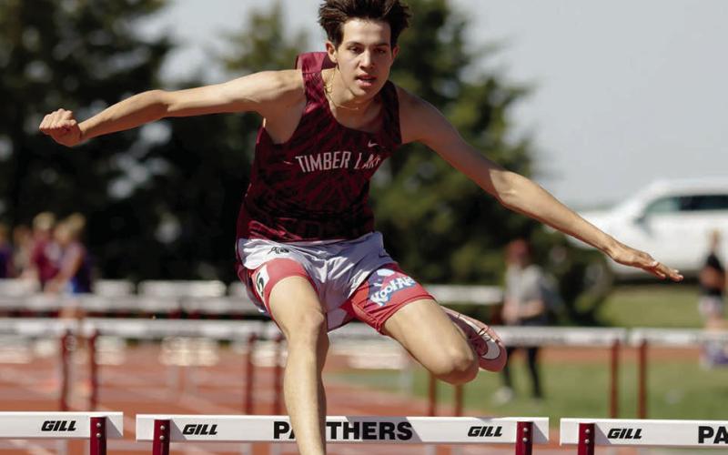 AT LEFT: Jackson Bigger clears a bar enroute to a first place finish in the 300 meter hurdles.  Photo by Marie DuPreez