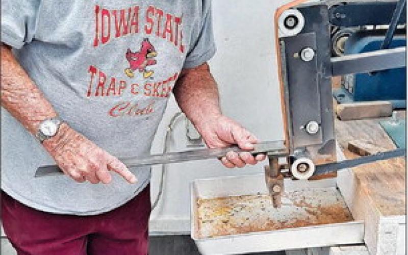 Wearing his protective mask, Jack uses the grinder on a piece of steel.