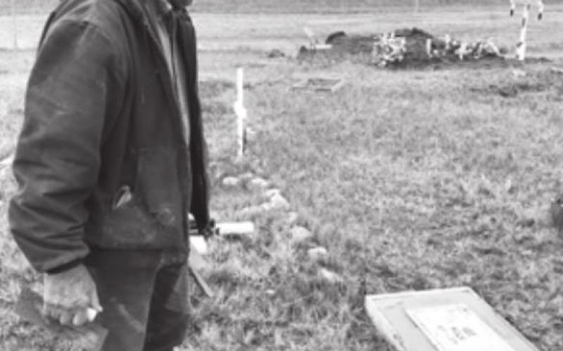 RIGHT: Deacon Larry Brown admires one of the granite headstones set into concrete.