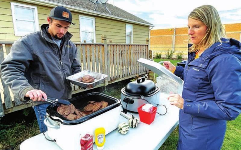 Student Brandt Ducheneaux and science teacher Luann Lindskov get beef and buffalo burgers ready for serving.