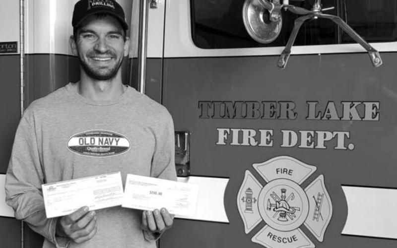 Scott Biegler of the Timber Lake Volunteer Fire Dept. accepts a $500 donation from Moreau-Grand Electric and Basin Electric.