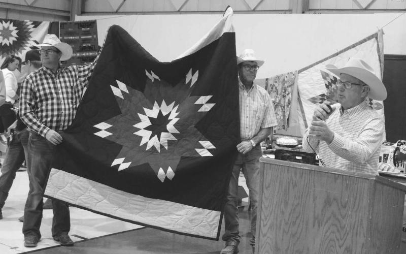 Taking bids on a star quilt are (L-R) Rusty Gebhardt, David Alley and auctoneer Brent Thiel.