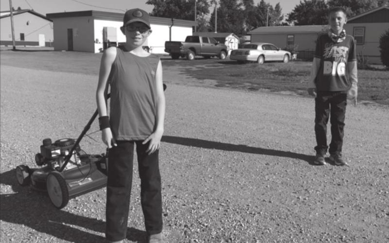Johnny Hoyt (LEFT) and Adam Meier, on the way to a lawn mowing job after school, show how it is to stand six feet apart.