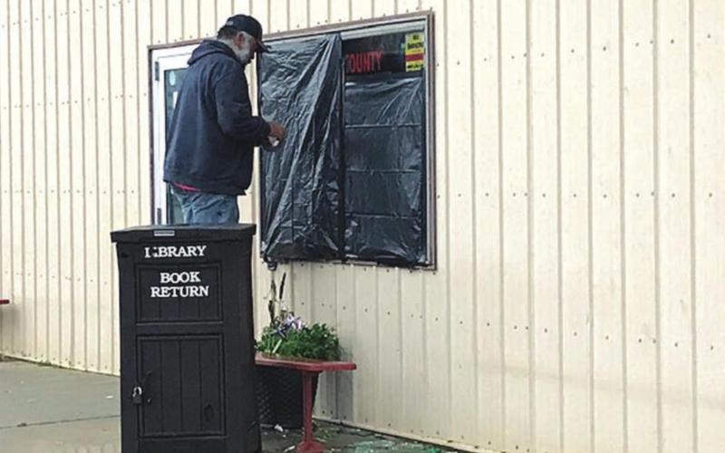 City maintenance manager Jerimiah Garon put temporary cover on the library windows.