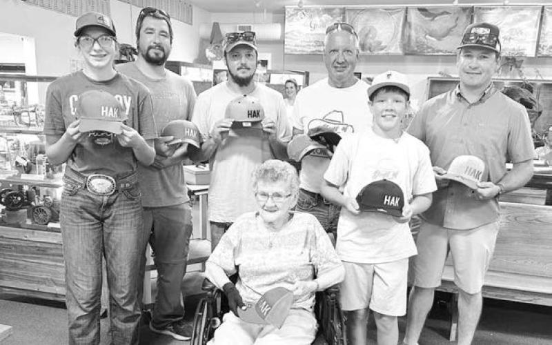 Pictured with Joyce Kraft and the HAK caps they all bought for chances to win a Herman Kraft knife are (l-r) Bricelyn Pederson of Broken Heart Ranch, Josh Biegler (who won the knife), Dalton Bender, David Biegler, Monroe Kraft (Tyrone), and Duffy Dupris.