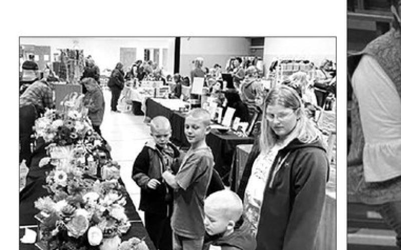 Twenty-seven vendors, some with two tables of wares, drew browsers at shoppers at the annual Fall Craft Fair at Timber Lake on November 5. Here Megan Zeug and sons (L-R) Eli, Isaac and Andrew admire wooden flowers.