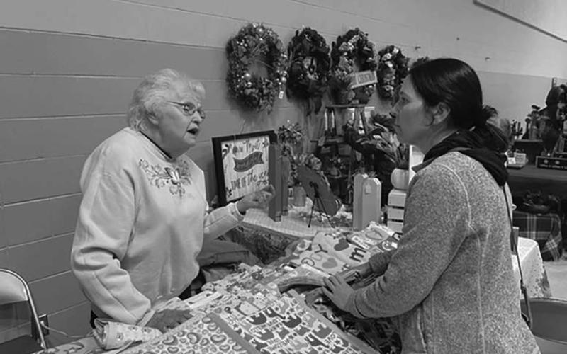 Carol Lipp (LEFT) has been making Christmas stockings and baby blankets for the Timber Lake Craft Fair for many years. Here she helps a customer, Renee Biegler.