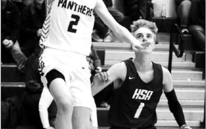 Junior guard Kyler Bollinger all but says “Cheese!” for the Topic camera while driving past Herreid-Selby defender Gavin Hannan (1) for a fingerroll layup during boys hoops action Monday, Dec. 19. Photo by Jon Flatland