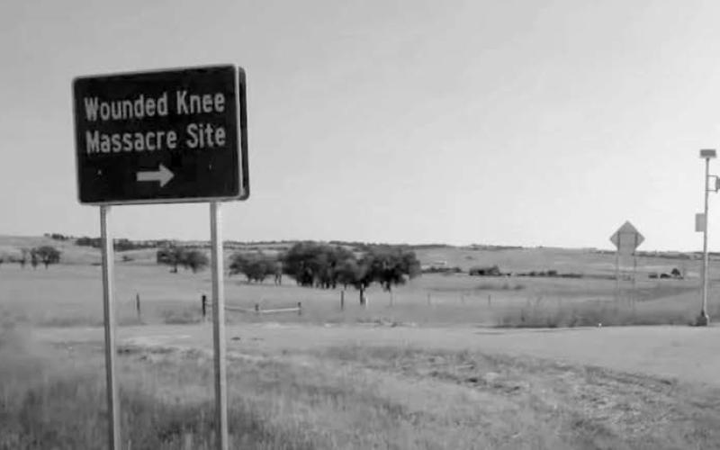 A state tourism sign points travelers in the direction of the Wounded Knee Massacre. South Dakota Searchlight photo by McKenzie Huber