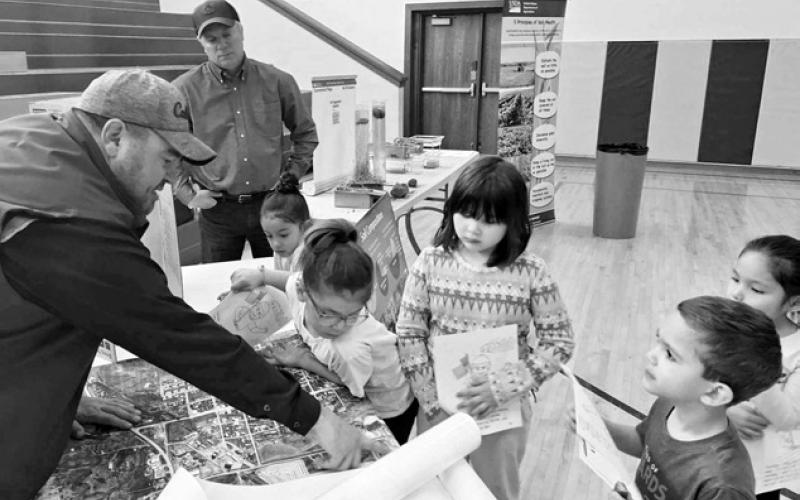 Dustin Jewett, from the USDA’s Natural Resources Conservation Service, shows some kindergarten students maps of the area.