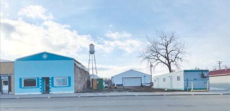 Demolition of the Schlosser building opened a spot where owner Stan Schlosser plans to move the small building shown at right to replace it. The blue building at left was formerly the Senior Center, then storage for Biegler Equipment, and later Lilian Turcotte’s vintage shop.