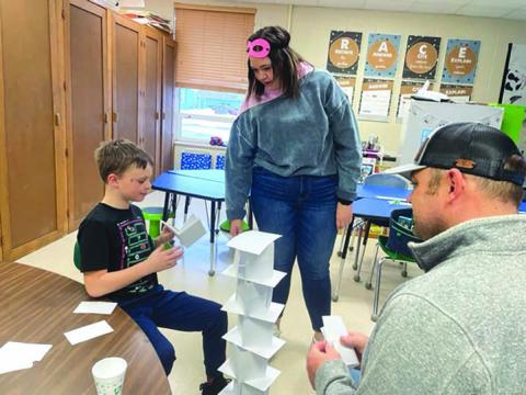 Keaton Jones builds a paper tower with only a little help from his teacher, Paige Bakken, and dad, Rio Jones.