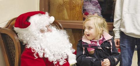 Five-year-old Lydia O’Bryan reacts with wide-eyed amazement at meeting Santa Claus during Timber Lake’s Holiday Extravaganza on Friday, Dec. 1. Lydia, daughter of Vicky Hulm and Taylor O’Bryan, said she’s been a good girl and asked Santa to bring her a stuffed cheetah. Photo by Roger Lawien
