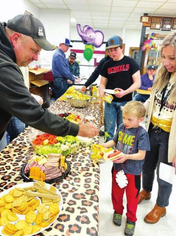 Volunteers from the Timber Lake Rodeo Association served a hot dog supper. Here Richard Gross helps Barrett Hermes to some veggies.