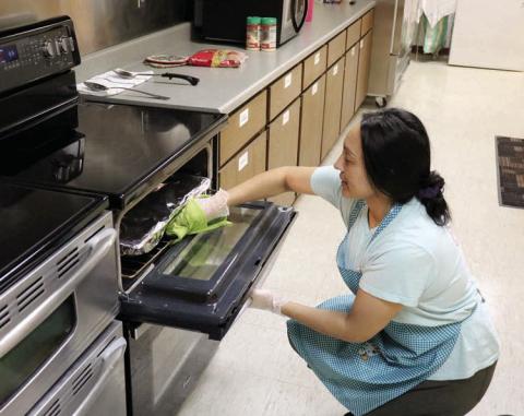 Gina Simon, manager of the Timber Lake-Isabel Senior Meals Site located in the Timber Lake Community Center, checks on a dish in the oven while preparing boxes for delivery through the Meals on Wheels Program. The program serves 25-30 clients per day, five-days-a-week. The program is slated to discontinue service this Friday, Sept. 13. Photo by Jon Flatland