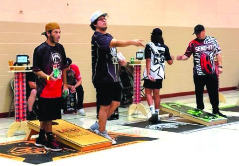 CJ Johnson, Scotty Landreaux, Bryson Andrews and Brad LeCompte compete in cornhole during a recent league night in Timber Lake. Below, James Traversie and Cadillac Ward display the Cheyenne River Cornhole League banner. Photos by Kathy Nelson