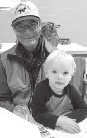 Cash Jones “reads” the program while he and his grandpa, Jay Jones, wait for the meeting to begin.