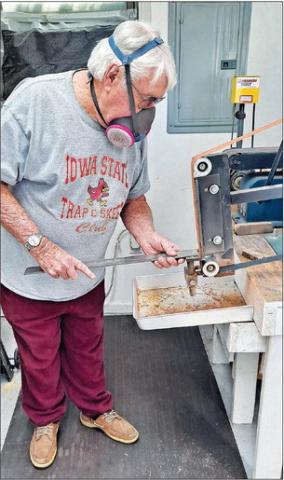 Wearing his protective mask, Jack uses the grinder on a piece of steel.
