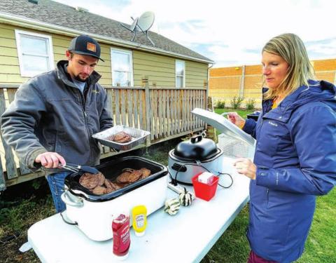Student Brandt Ducheneaux and science teacher Luann Lindskov get beef and buffalo burgers ready for serving.