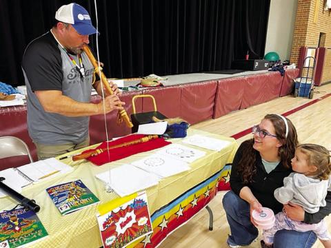 Mark Mindt (LEFT), creator of Koda the Warrior, a Native American superhero, plays the flute for Shanna Martin and her daughter, Crozbee, at the Timber Lake Elementary School Family Fun Night on March 23. Mindt visited elementary classes throughout the day prior to taking part in the Family Fun Night. (More on page 16) Photo by Kathy Nelson