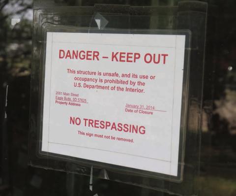 A sign on the front door of the former CRST Tribal Headquarters building in Eagle Butte shows Jan. 31, 2014, as the date it was closed and abandoned due to mold and other issues. Photo by Jon Flatland