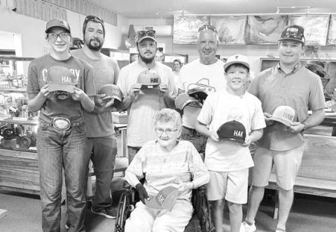 Pictured with Joyce Kraft and the HAK caps they all bought for chances to win a Herman Kraft knife are (l-r) Bricelyn Pederson of Broken Heart Ranch, Josh Biegler (who won the knife), Dalton Bender, David Biegler, Monroe Kraft (Tyrone), and Duffy Dupris.