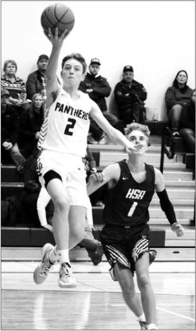 Junior guard Kyler Bollinger all but says “Cheese!” for the Topic camera while driving past Herreid-Selby defender Gavin Hannan (1) for a fingerroll layup during boys hoops action Monday, Dec. 19. Photo by Jon Flatland