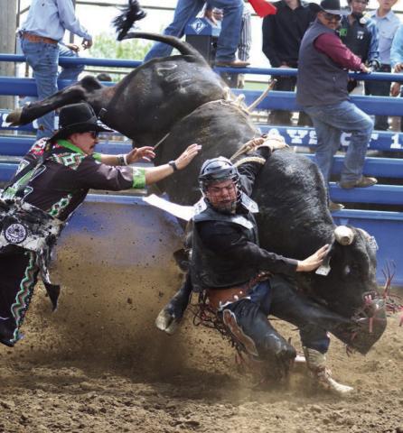 Faith bull rider Roy Antrim found himself someplace a bull rider never wants to be - hung up and in the well - at the Timber Lake High School Rodeo last Saturday, May 25. Bull fighter Layton Woodbury (left) moves in to try and free Antrim, who eventually escaped bruised but otherwise uninjured. Photo by Jon Flatland