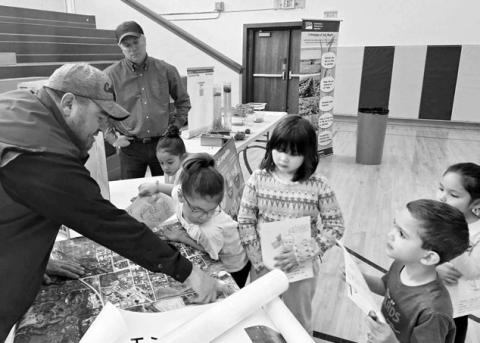 Dustin Jewett, from the USDA’s Natural Resources Conservation Service, shows some kindergarten students maps of the area.