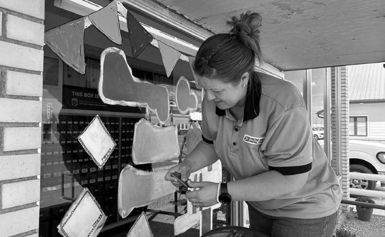 Timber Lake Post Office employee Amy Bridges paints the front window of the Post Office with a welcome back to school for students. The 2025-26 school year got underway Monday, Aug. 18. Photo by Jon Flatland