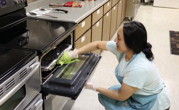 Gina Simon, manager of the Timber Lake-Isabel Senior Meals Site located in the Timber Lake Community Center, checks on a dish in the oven while preparing boxes for delivery through the Meals on Wheels Program. The program serves 25-30 clients per day, five-days-a-week. The program is slated to discontinue service this Friday, Sept. 13. Photo by Jon Flatland