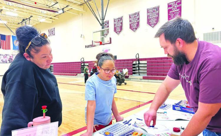 Sophia Ley and her aunt, Colette Brown Otter, visit Walker Rose’s table to see what they can learn.