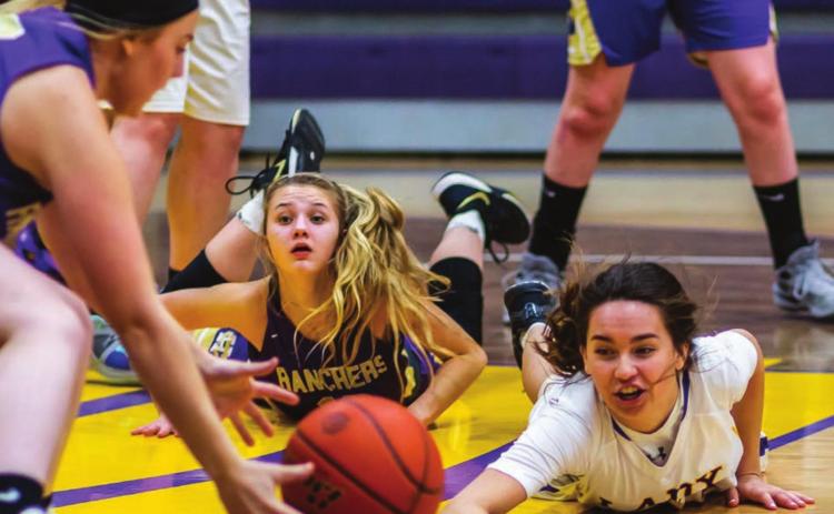 Harding County’s Bailey Verhulst (LEFT) scoops up the basketball after Dupree’s RaeLynn Vines (RIGHT) dove to keep it away from Rancher Reese Hunsucker (CENTER) during the Little Moreau Conference game.