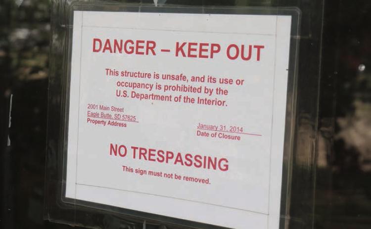 A sign on the front door of the former CRST Tribal Headquarters building in Eagle Butte shows Jan. 31, 2014, as the date it was closed and abandoned due to mold and other issues. Photo by Jon Flatland